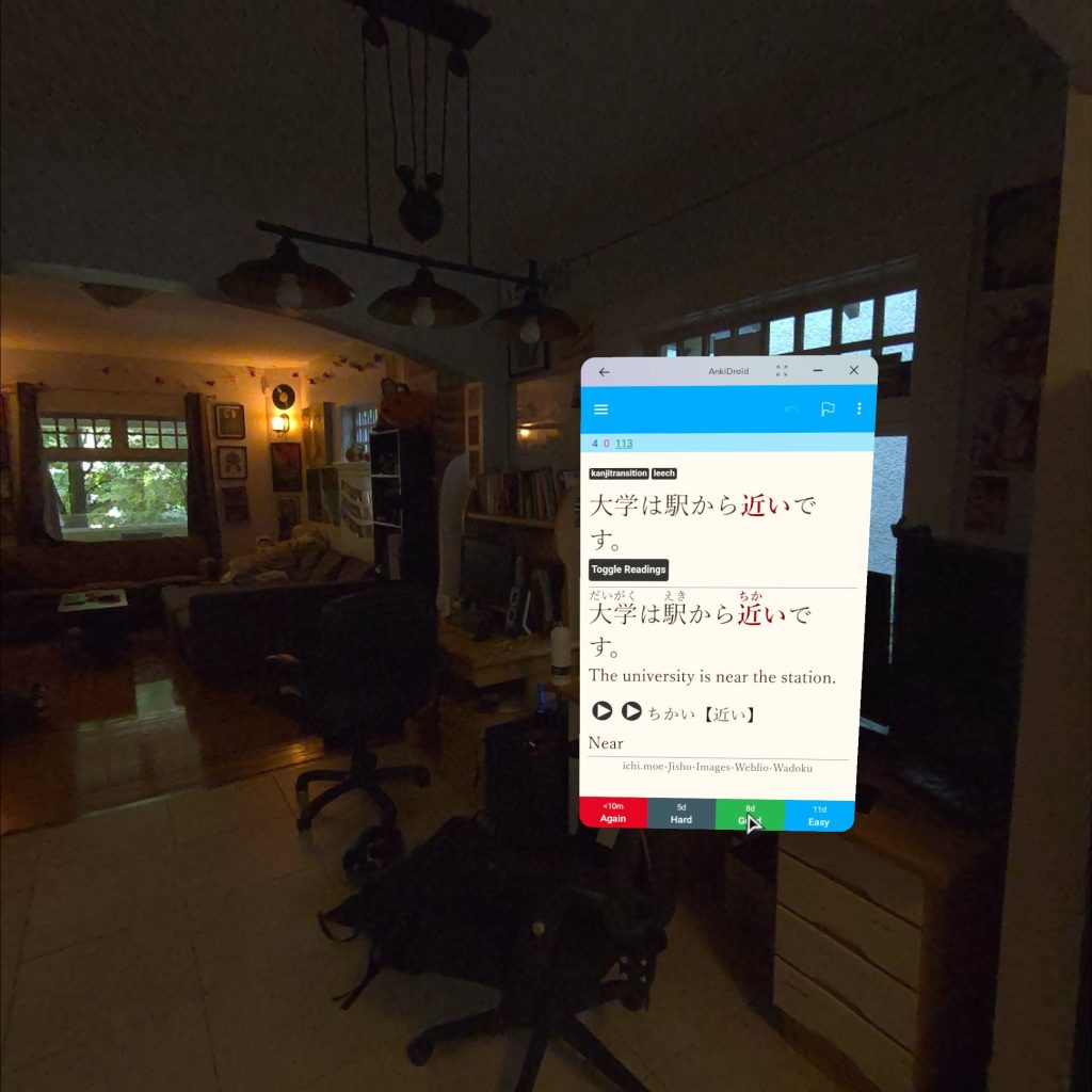 The user interface for AnkiDroid displaying a Japanese language flashcard in a virtual display, hovering in Riley's living room.