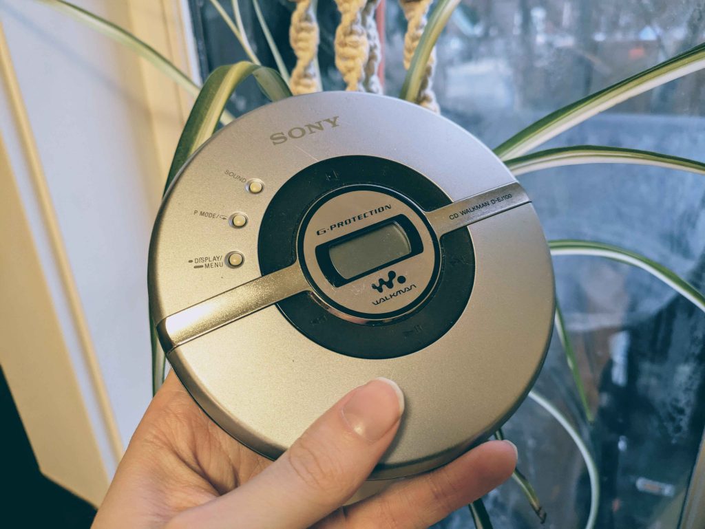 The Sony D-EJ100 portable CD player, an all silver device being held up next to a window.